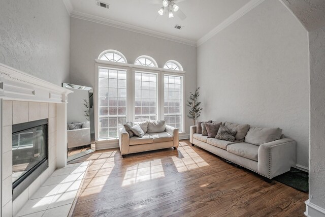 living room featuring light hardwood / wood-style floors, crown molding, ceiling fan, and a fireplace