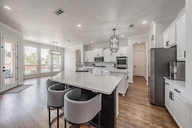 kitchen with white cabinetry, appliances with stainless steel finishes, hardwood / wood-style flooring, and a large island