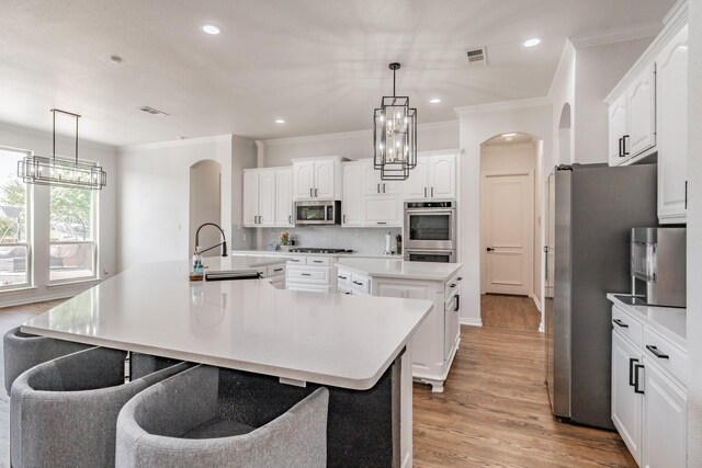 kitchen with stainless steel appliances, light hardwood / wood-style floors, a spacious island, sink, and white cabinets