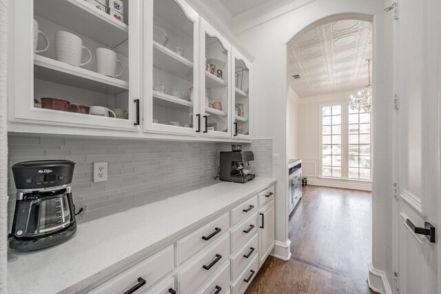 bar with decorative backsplash, crown molding, and dark hardwood / wood-style floors