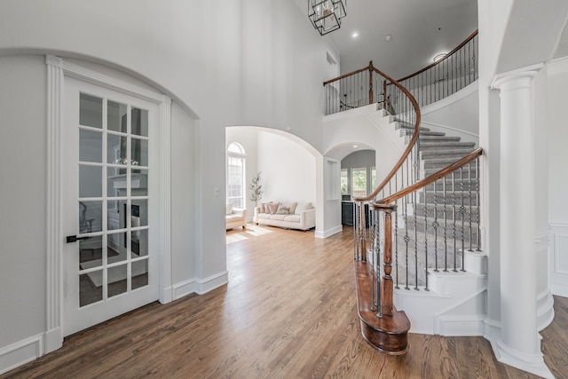 entrance foyer with a towering ceiling, hardwood / wood-style floors, and ornate columns