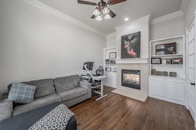 living room featuring ceiling fan, wood-type flooring, ornamental molding, and a tile fireplace