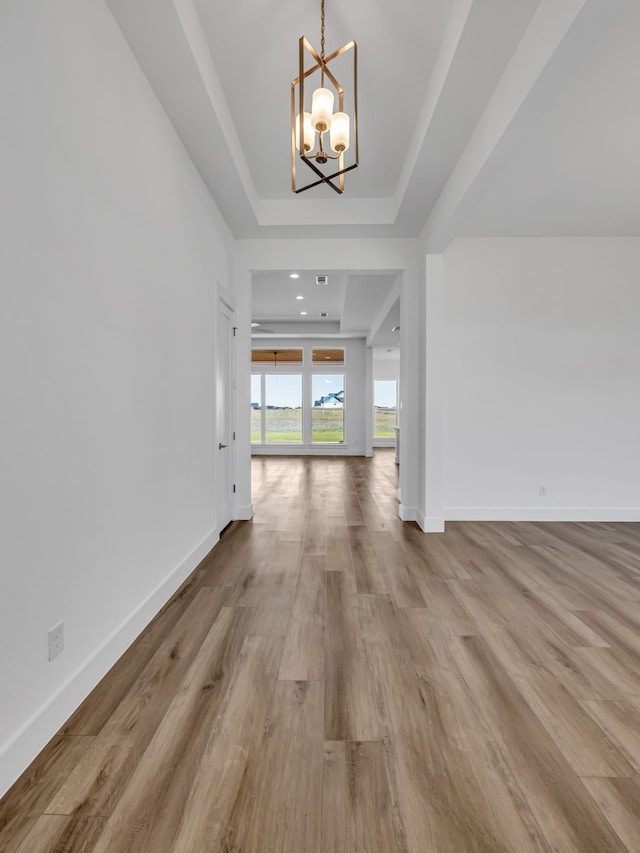 interior space with light hardwood / wood-style floors, an inviting chandelier, and a tray ceiling