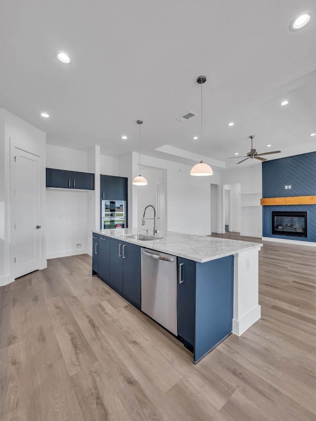 kitchen with pendant lighting, dishwasher, sink, blue cabinetry, and a spacious island