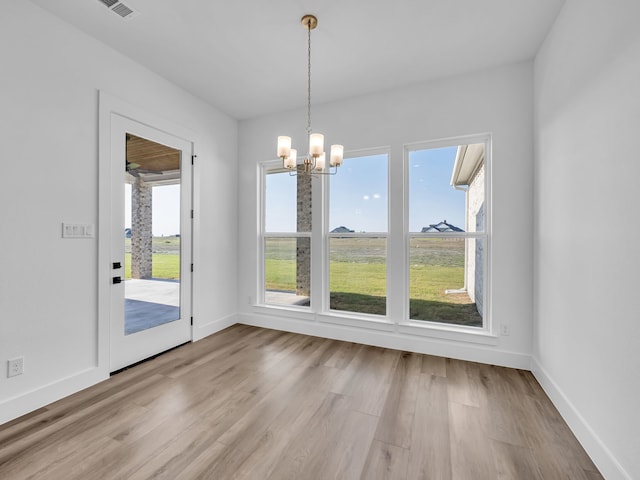 unfurnished dining area featuring a notable chandelier and light hardwood / wood-style floors