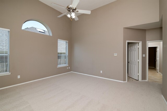 carpeted spare room featuring ceiling fan and high vaulted ceiling