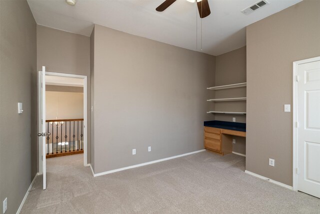 unfurnished bedroom featuring ceiling fan, built in desk, and carpet