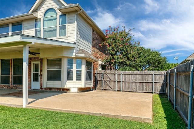 rear view of house featuring ceiling fan, a patio, and a lawn