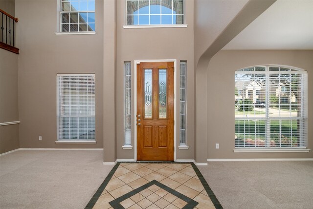 entrance foyer featuring a towering ceiling and light colored carpet