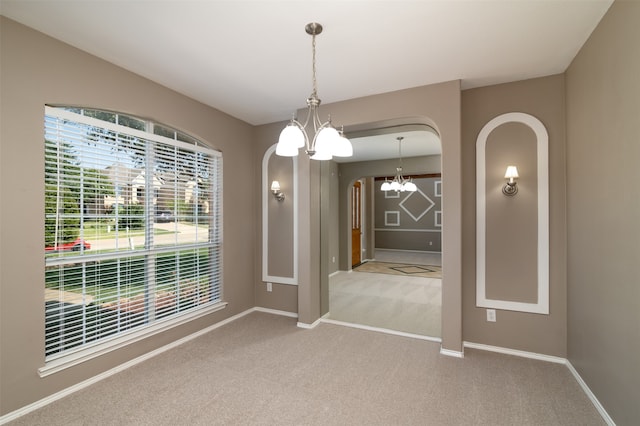 carpeted empty room featuring an inviting chandelier