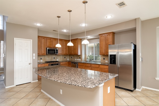 kitchen featuring decorative backsplash, light tile patterned floors, stainless steel appliances, and a kitchen island