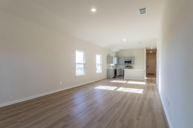 unfurnished living room with vaulted ceiling and light wood-type flooring