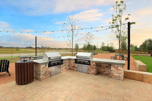 patio terrace at dusk featuring an outdoor kitchen and grilling area