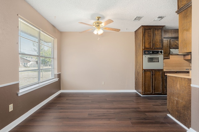 kitchen with ceiling fan, oven, a textured ceiling, and dark hardwood / wood-style floors