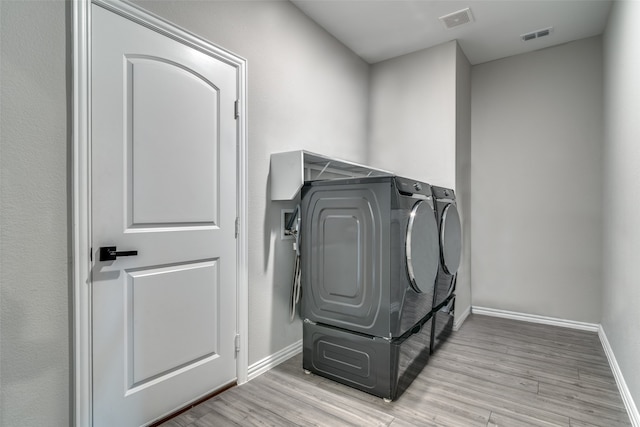 laundry area featuring washing machine and dryer and light wood-type flooring