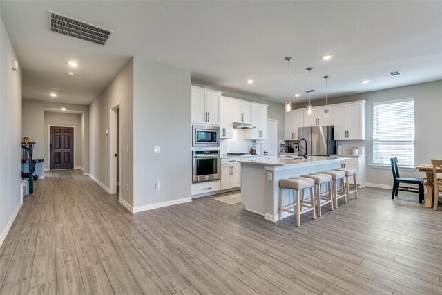 kitchen featuring stainless steel appliances, white cabinetry, and light hardwood / wood-style floors