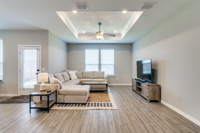 living room featuring ceiling fan, a raised ceiling, and light hardwood / wood-style floors