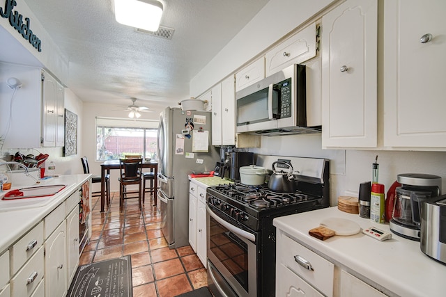 kitchen featuring a textured ceiling, appliances with stainless steel finishes, white cabinets, ceiling fan, and sink