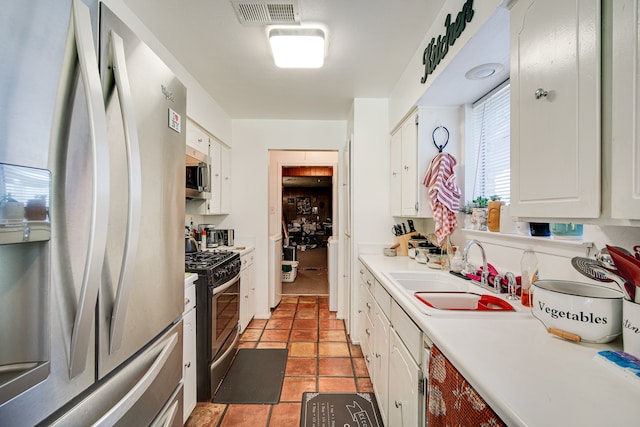 kitchen with light tile patterned flooring, appliances with stainless steel finishes, sink, and white cabinetry