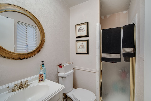 bathroom featuring a shower with shower door, vanity, and toilet