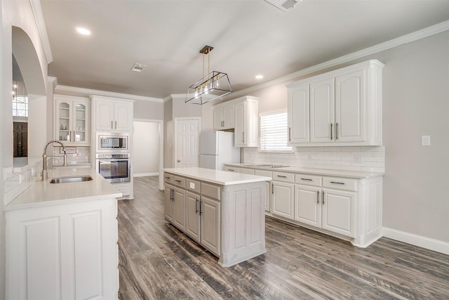 kitchen featuring white cabinets, backsplash, appliances with stainless steel finishes, sink, and a kitchen island