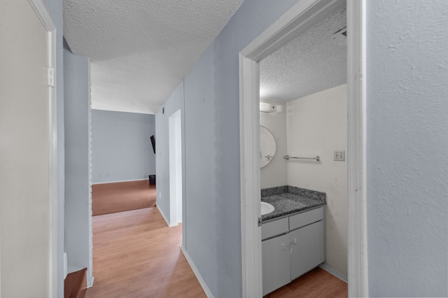 corridor featuring a textured ceiling, sink, and hardwood / wood-style flooring