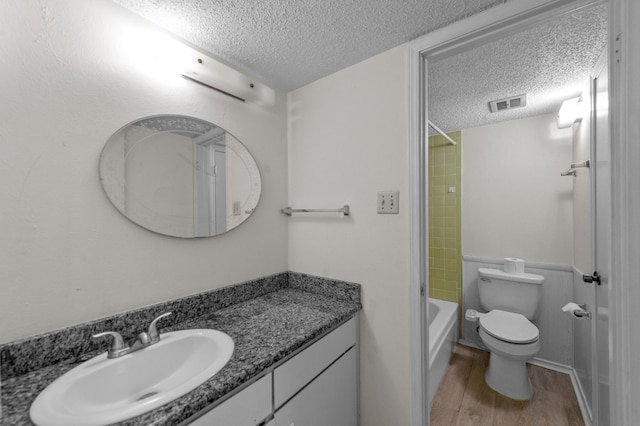 full bathroom with wood-type flooring, a textured ceiling, vanity, and toilet