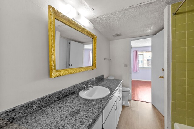 full bathroom featuring a textured ceiling, hardwood / wood-style flooring, toilet, vanity, and bathing tub / shower combination