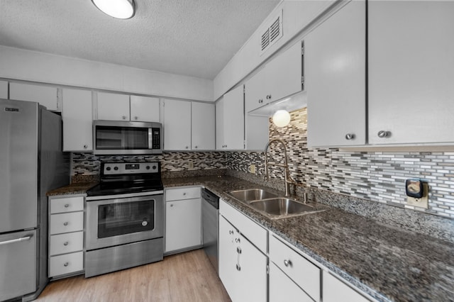 kitchen with sink, stainless steel appliances, backsplash, and light wood-type flooring