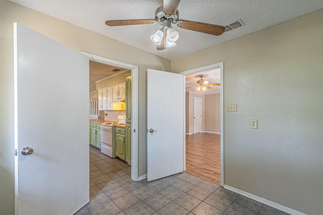 tiled empty room featuring ceiling fan and a textured ceiling