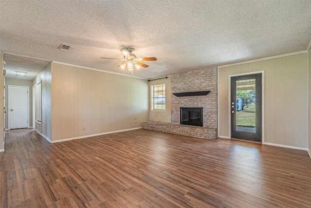 unfurnished living room with dark wood-type flooring, ceiling fan, crown molding, and a brick fireplace