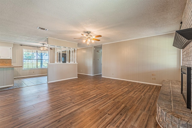 unfurnished living room featuring a brick fireplace, dark wood-type flooring, and ceiling fan