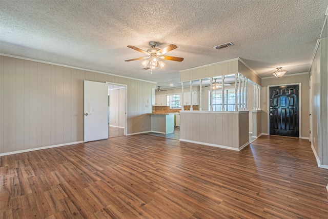 unfurnished living room with crown molding, ceiling fan, dark hardwood / wood-style flooring, and a textured ceiling