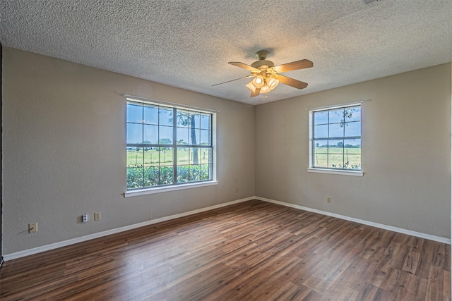 empty room featuring a textured ceiling, dark hardwood / wood-style floors, and a healthy amount of sunlight