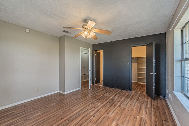 unfurnished bedroom featuring multiple windows, a closet, dark hardwood / wood-style floors, and a textured ceiling