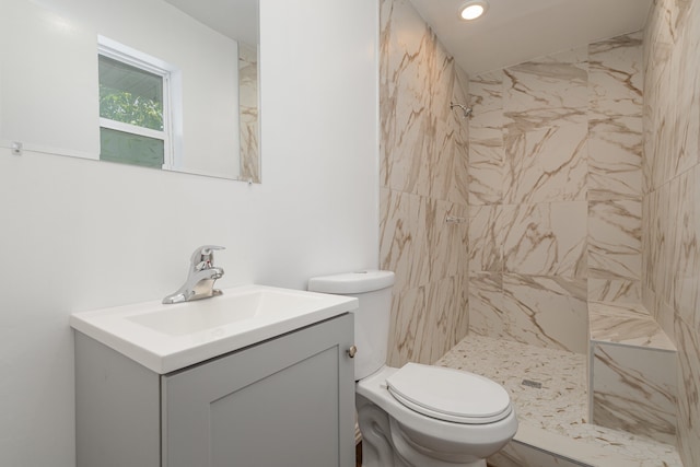 bathroom featuring vanity, a tile shower, and toilet