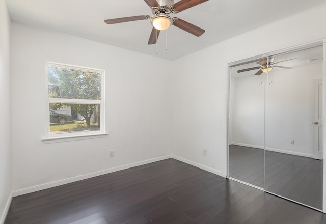 unfurnished bedroom with dark wood-type flooring, ceiling fan, and a closet