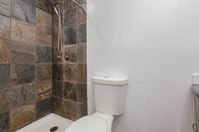 bathroom with a tile shower and toilet