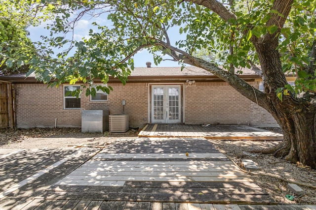 rear view of house with french doors, a wooden deck, and central AC