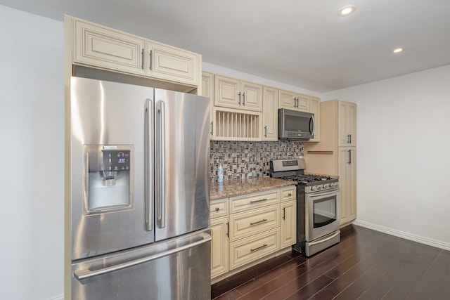 kitchen with appliances with stainless steel finishes, backsplash, and cream cabinets