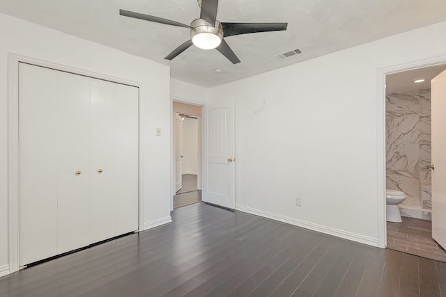 unfurnished bedroom featuring dark hardwood / wood-style flooring, connected bathroom, ceiling fan, and a closet