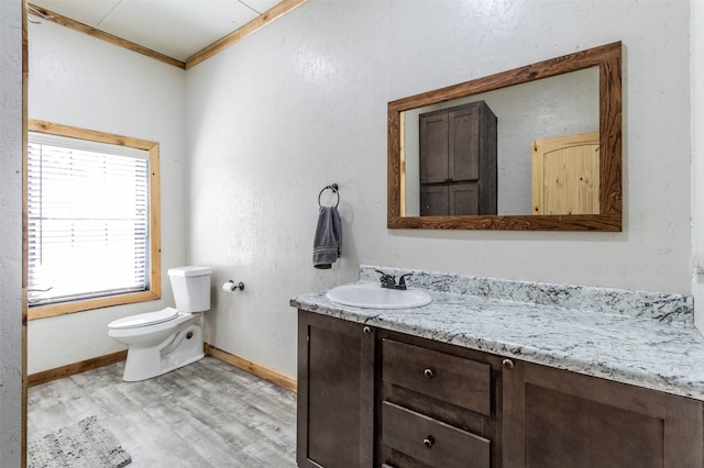 bathroom with hardwood / wood-style floors, toilet, crown molding, and vanity