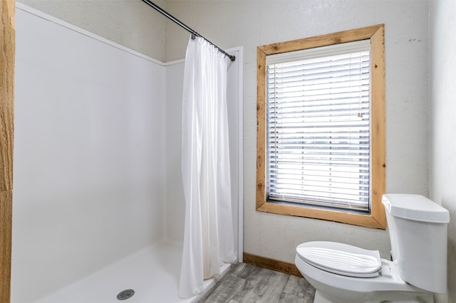 bathroom featuring a healthy amount of sunlight, toilet, a shower with curtain, and hardwood / wood-style floors