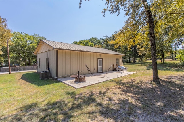 back of property featuring cooling unit, a fire pit, a patio area, and a lawn