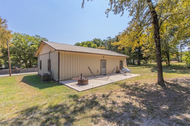 rear view of property with a fire pit, a yard, cooling unit, and a patio