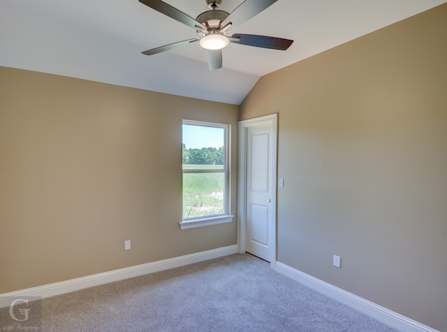 empty room with ceiling fan, vaulted ceiling, and light colored carpet