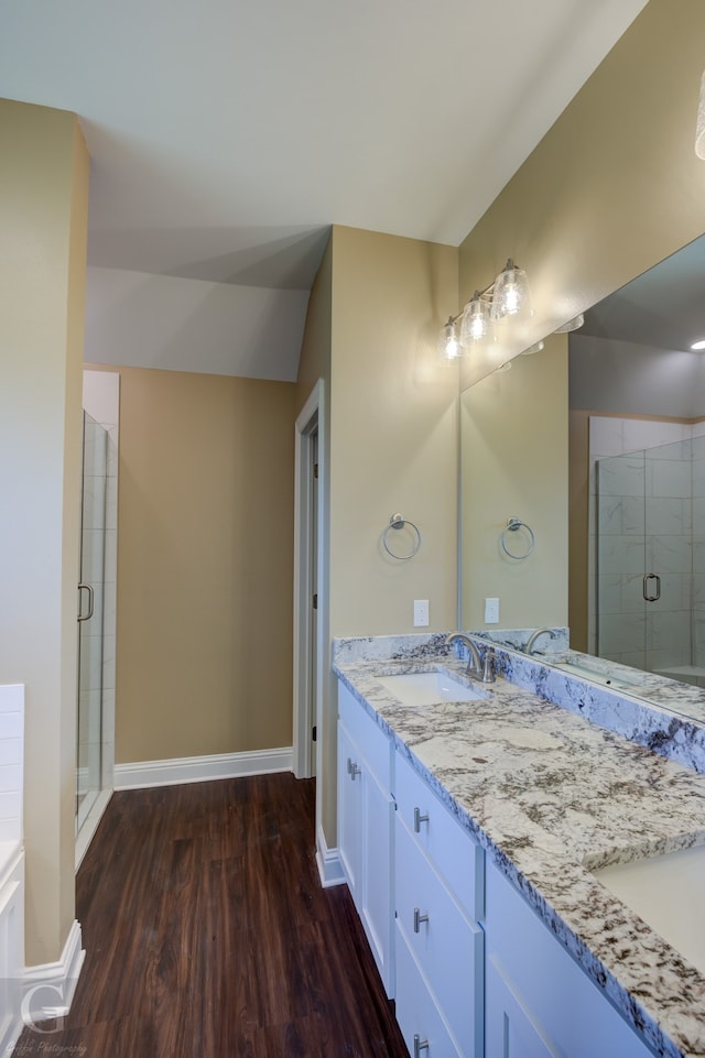 bathroom featuring dual bowl vanity, wood-type flooring, and an enclosed shower