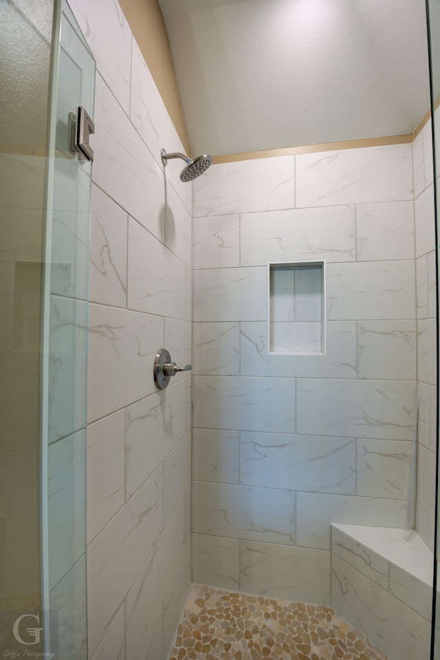 bathroom featuring lofted ceiling and a tile shower