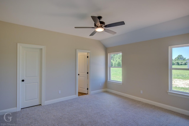 unfurnished bedroom with vaulted ceiling, ceiling fan, carpet floors, and multiple windows