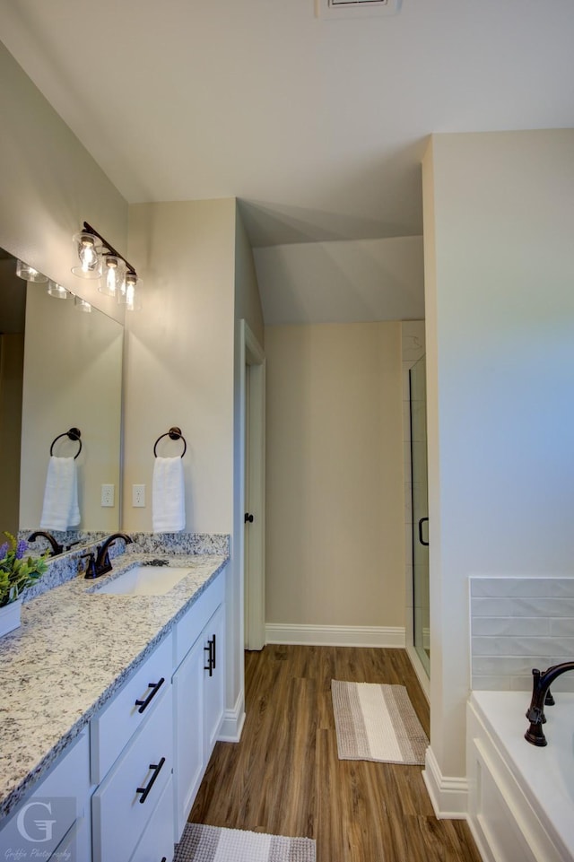 bathroom featuring wood-type flooring, plus walk in shower, and vanity